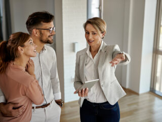 Happy real estate agent talking to a couple while showing them a new apartment.