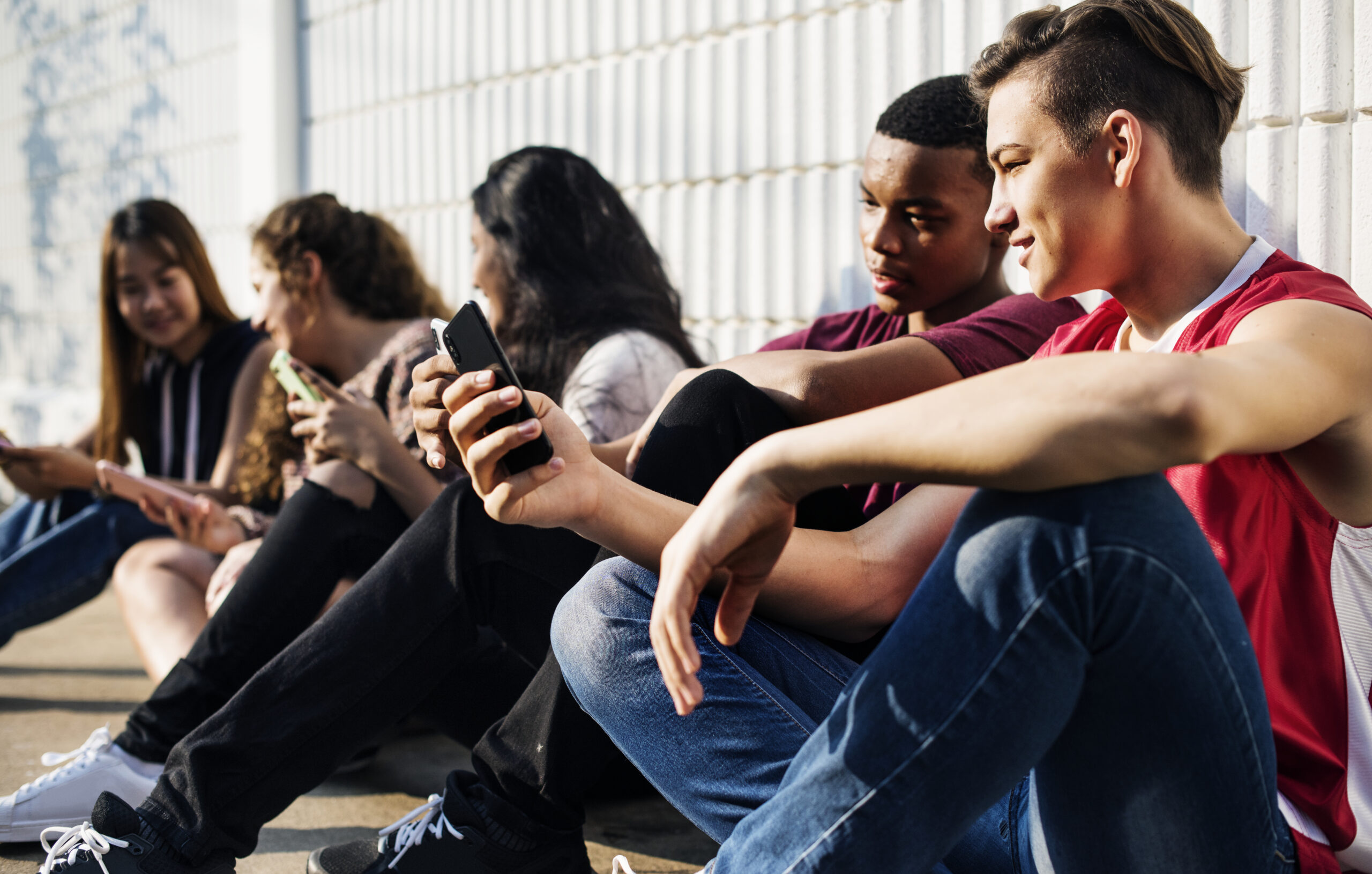 Group of young teenager friends chilling out together using smartphone social media concept